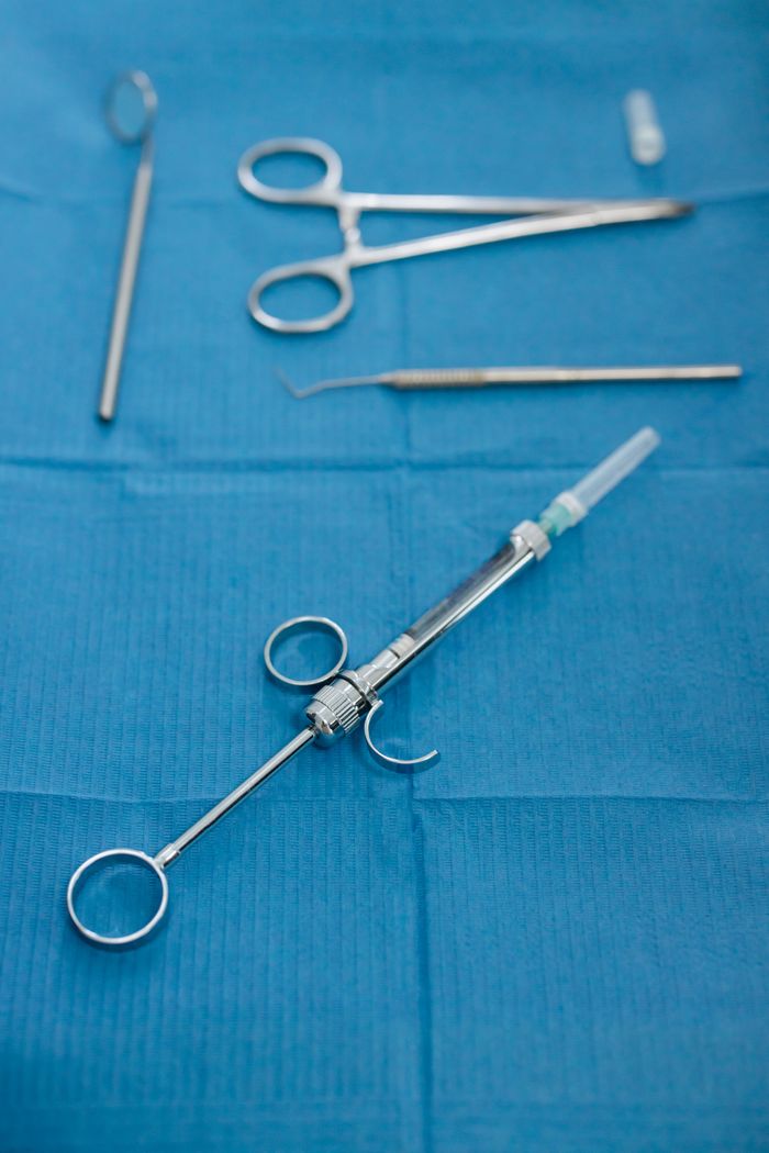 Detailed image of dental instruments including a syringe on a blue surface, emphasizing dental care.